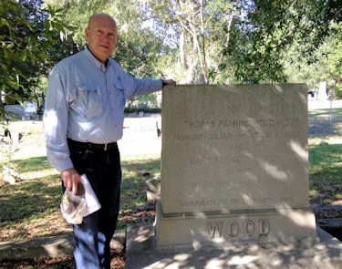 David Rice stands next to a headstone in Oakdale Cemetery. Photo: N.C. Health News
