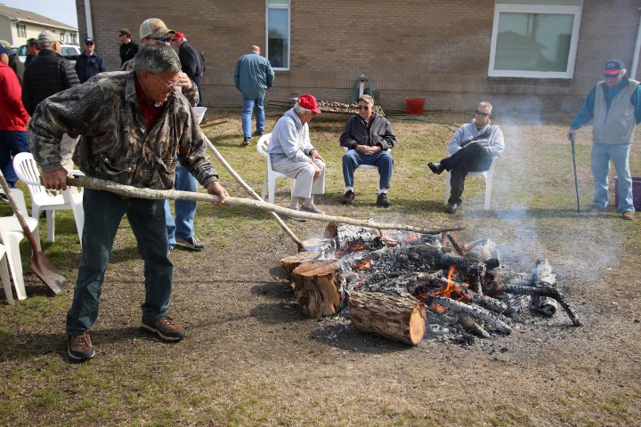 Members of the Salter Path Men's Club stoke the fire in preparation for steaming oysters. Photo: Sam Bland