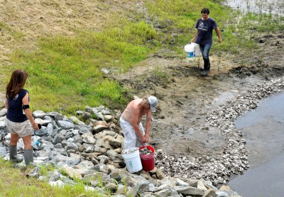 Coastal scientist Lexia Weaver looks on while EWNC members Dmitry Shevchenko and Sergey Haymahan carry buckets of oyster shells. Photo by Todd Miller.