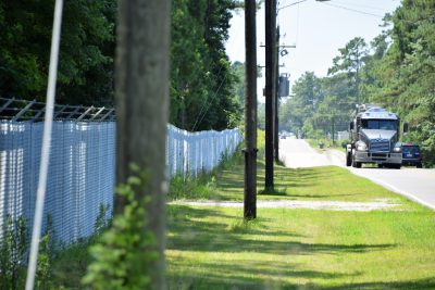 Traffic passes by the fenced-off Kerr-McGee Chemical Corp. site that’s just off the highway leading into Navassa. Photo: Mark Hibbs