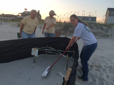 Michele Lamping, right, smooths sand to provide baby turtles a clear path to the ocean during a nest sitting with volunteers Mike and Barb Basher. Photo contributed