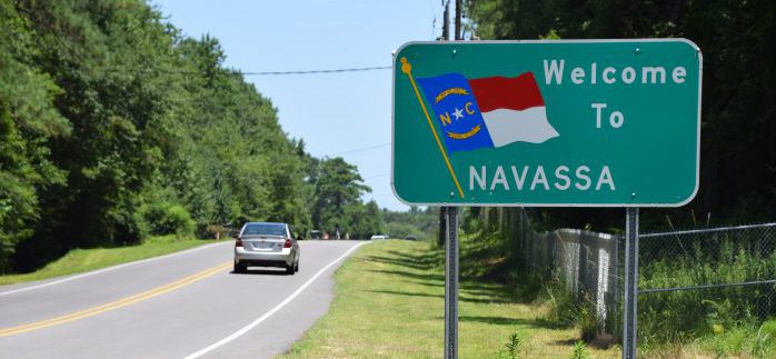 A welcome sign and the fenced-off Kerr-McGee Chemical Corp. site greet visitors at the Navassa city limits. Photo: Mark Hibbs