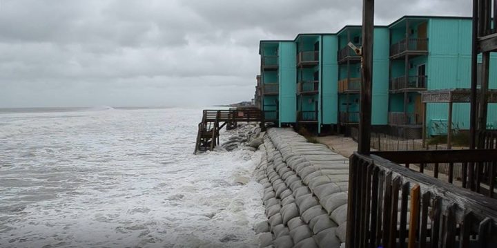 Photograph showing the bulkhead in North Topsail Beach, N.C. The tides are hitting the buildings, and the beach is almost entirely destroyed.