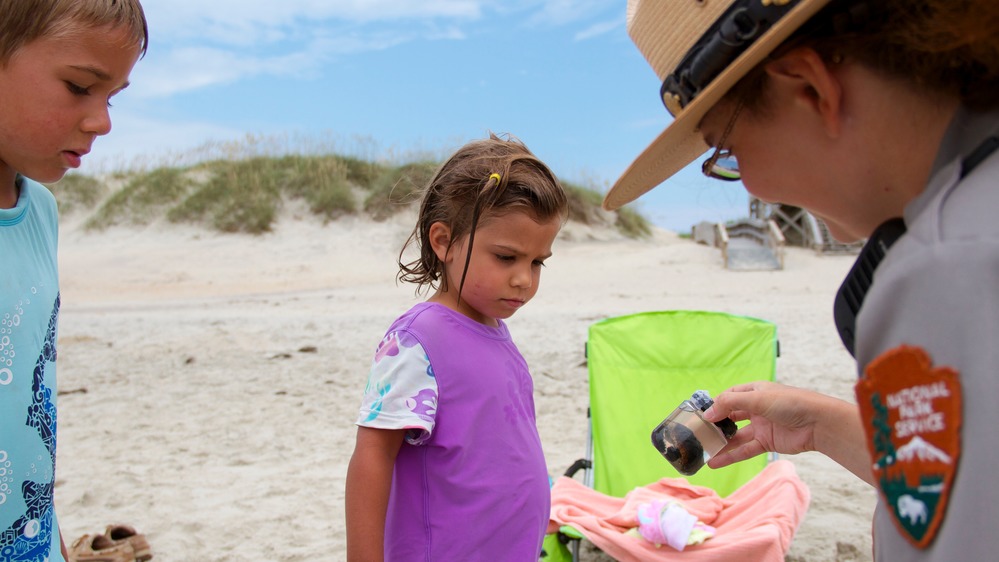 A ranger at Cape Hatteras National Seashore talks to young beachgoers about sea turtles. During National Outdoor Month in June, land managers urge visitors to protect natural resources. Photo: National Park Service 