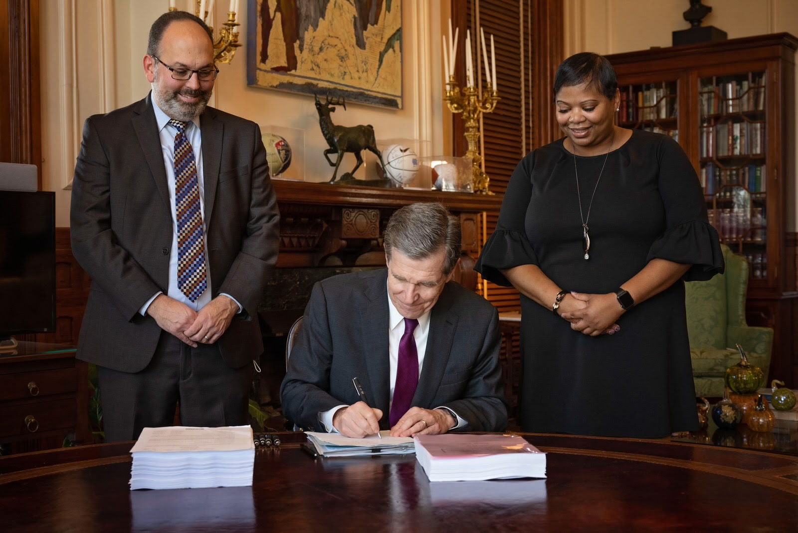 Gov. Roy Cooper, seated, signs the state budget and two bills. Photo: Governor's office