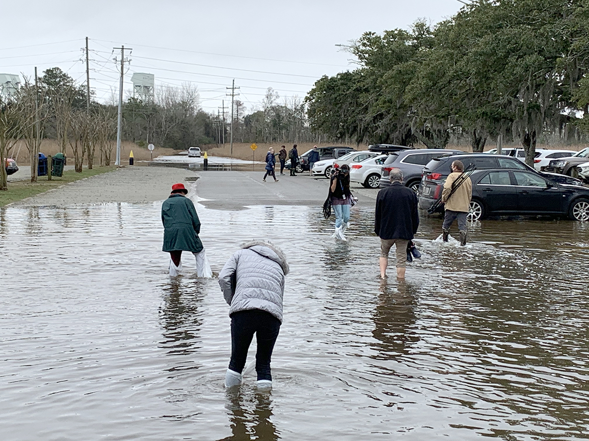 Attendees of Wednesday’s press conference wade through floodwaters caused by the rising tide inundating portions of the historic site’s parking lot near the banks of the Cape Fear River. The ship is just south of land being eyed as the site of a trio of high-rise condominiums. Photo: Trista Talton