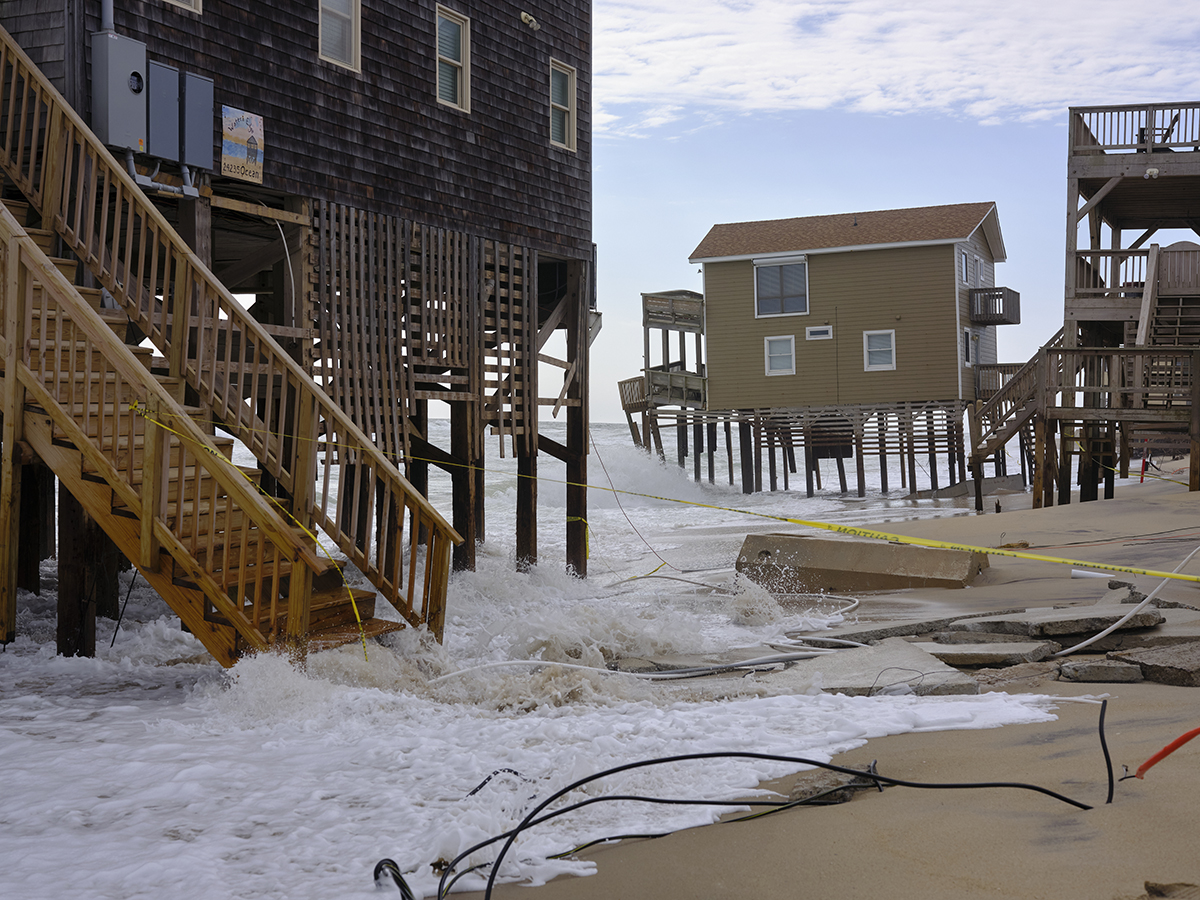 Waves, broken concrete, exposed septic systems, warning tape and debris surround houses teetering at the edge of the Atlantic Ocean just off Ocean Drive in Rodanthe, Friday, March 4. Photo: Justin Cook