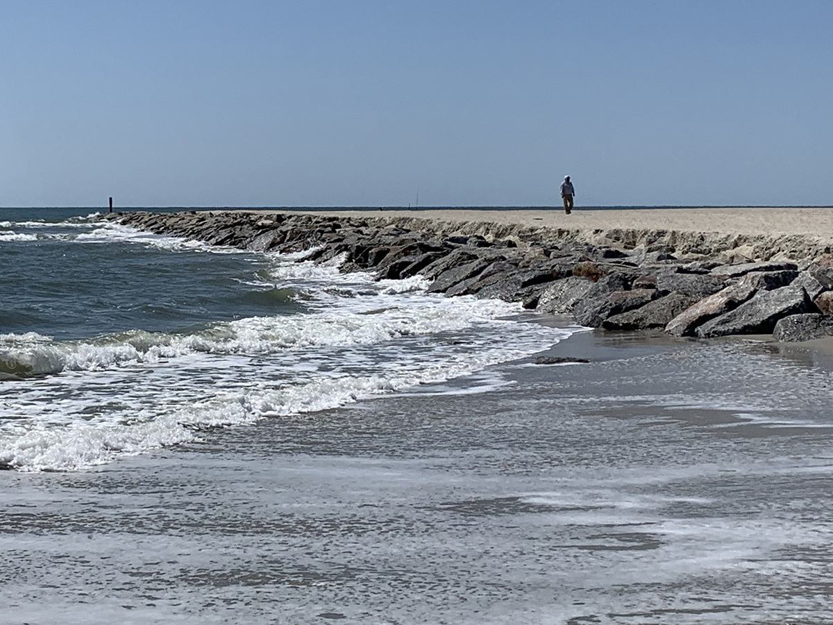 A beachgoer strolls alongside Ocean Isle Beach's recently completed terminal groin at the east end of the Brunswick County town. Photo: Trista Talton