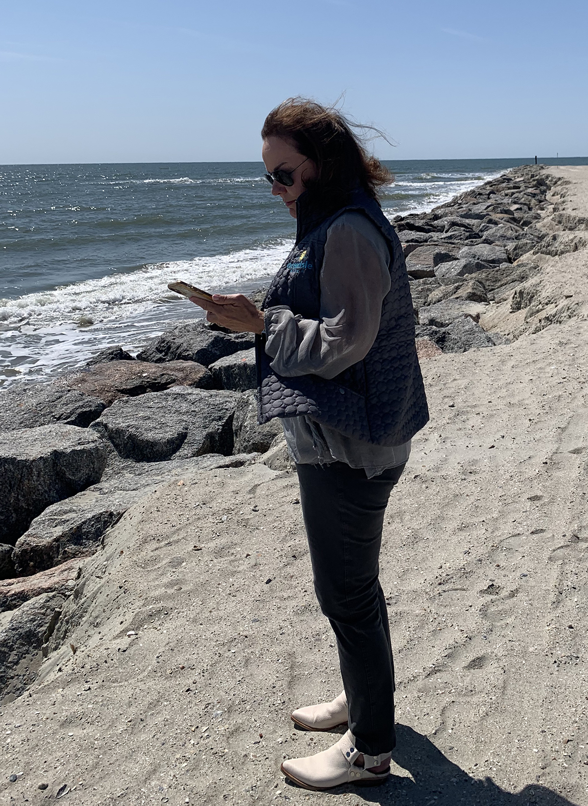 Ocean Isle Beach Mayor Debbie Smith checks her phone while standing next to the town’s recently completed terminal groin. Photo: Trista Talton