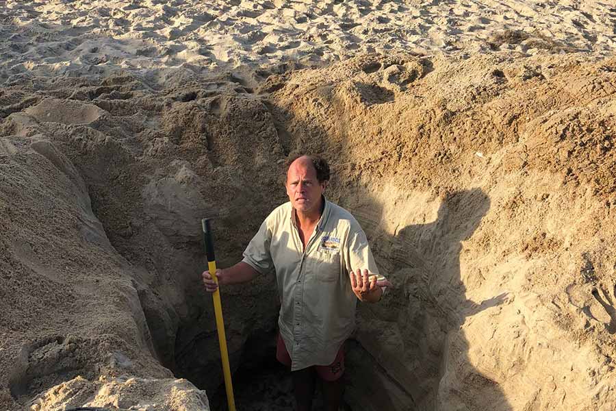 Dave Elder stands in a massive hole left on the beach. Photo: Kill Devil Hills Facebook
