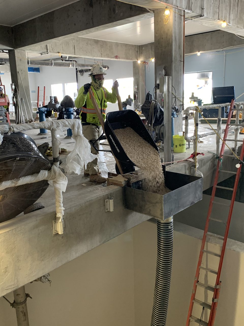 A construction worker dumps gravel into a pipe leading to the bottom of one of the new granular activated carbon filtration compartments inside the newest addition to the Cape Fear Public Utility Authority's Sweeney Treatment Plant in downtown Wilmington. Photo: Trista Talton