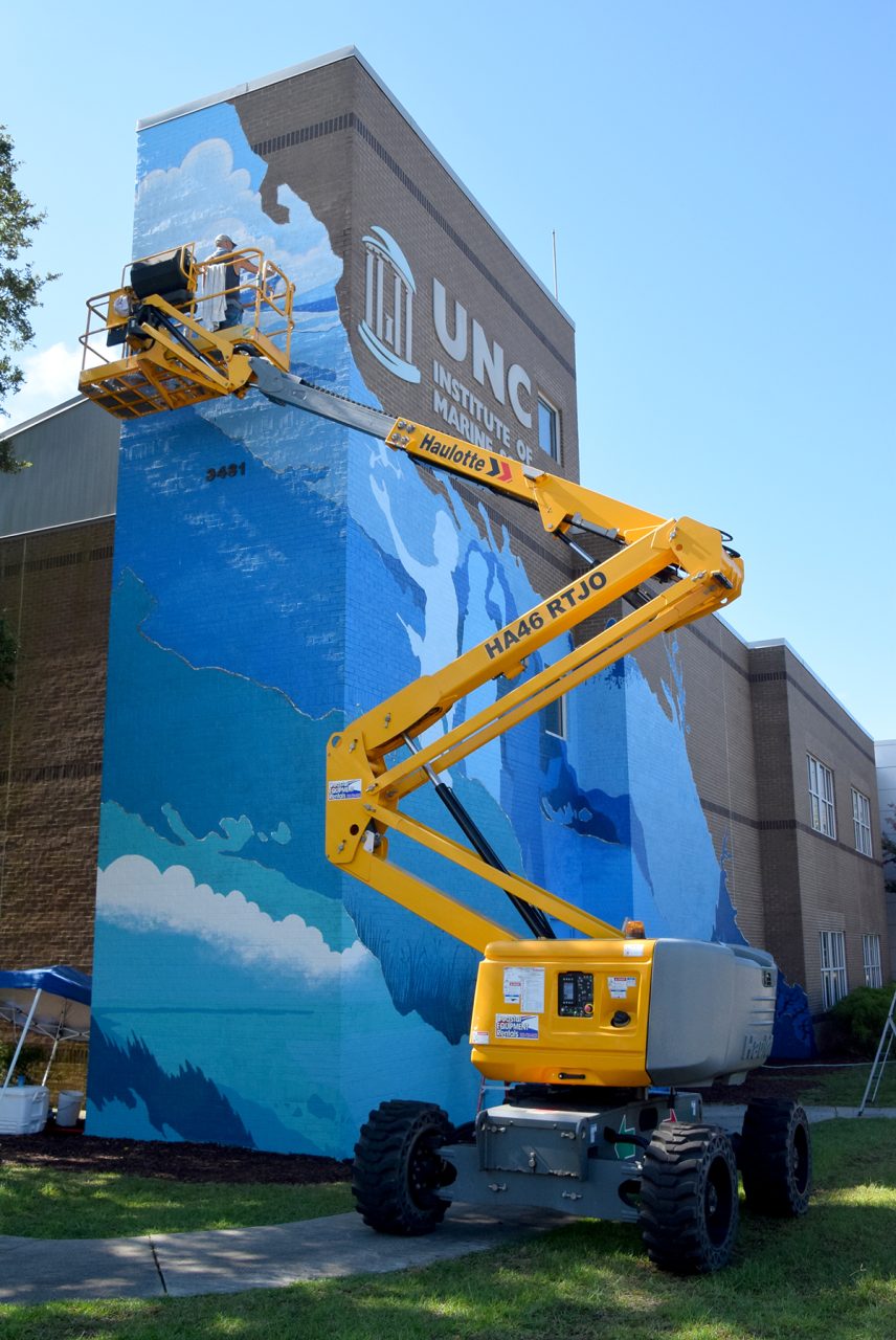 Max Dowdle adds detail to his interpretation of the institute's research vessel Capricorn at the upper reaches of his mural underway Tuesday in Morehead City. Photo: Mark Hibbs