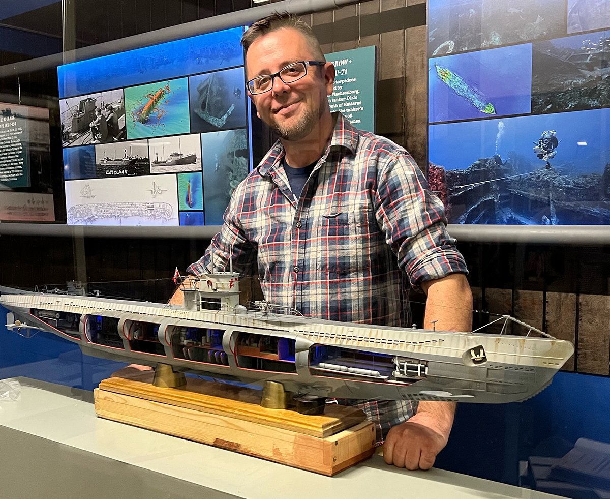 Mark Mills poses with the cutaway model of the U-522 that he built on display as part of the Graveyard of the Atlantic Museum’s new  "Operation Drumbeat" exhibit. Photo courtesy of the museum and the N.C. Division of Archives and History 