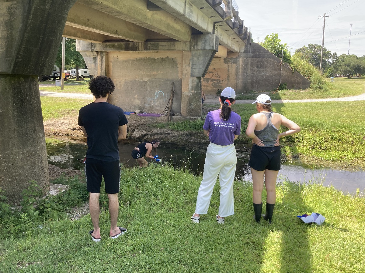 Blake Todzo, left, Angela Jiang and Amy Buckalew wait as Rebecca Drohan with Coastal Carolina Riverwatch collects wate samples. Photo: Laura Givens/Duke University