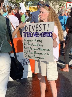 A protestor holds a sign calling for divestment from Chemours. Photo: Trista Talton