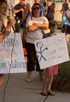 A young protestor holds a sign outside of the Leland Cultural Arts Center during an open house about Chemours' expansion plan. Photo: Trista Talton