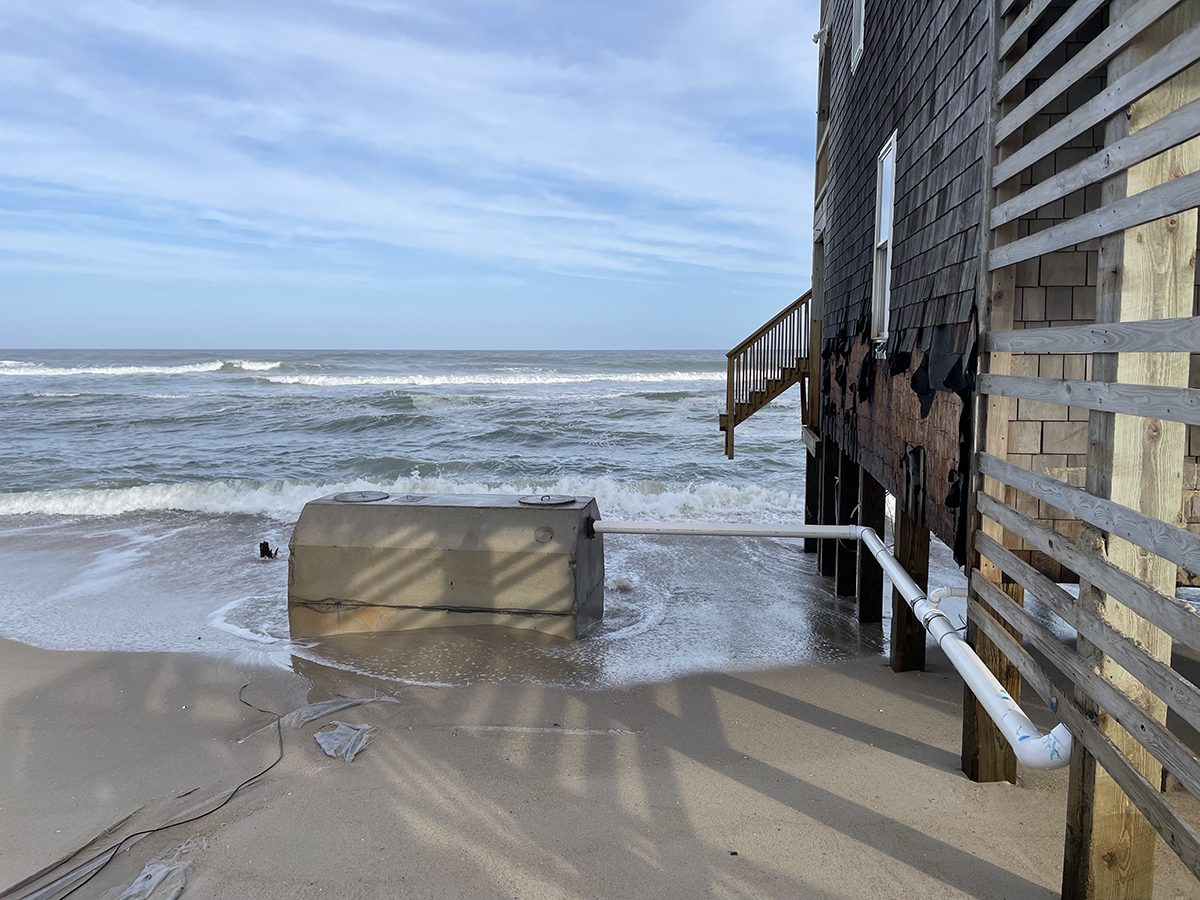 Waves break around an exposed septic tank with no visible drain field at a rental house on the public beach in Rodanthe. Photo: National Park Service via Dare County Planning Department.