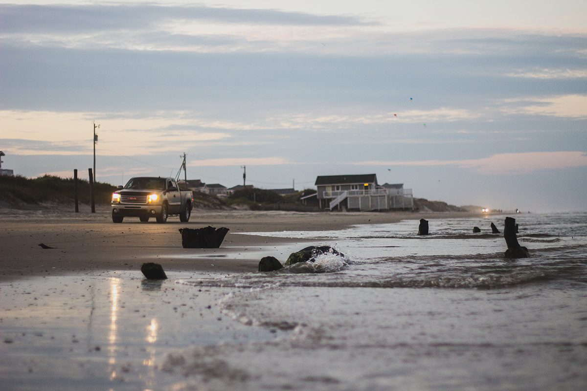 The headlights of four-wheel-drive vehicles light the way on the beach road that serves as the only access in and out of Carova. Photo: Josee Molavi