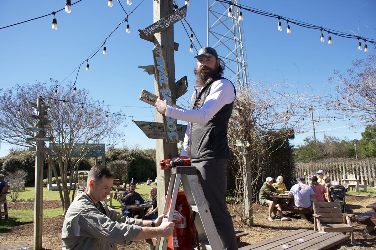 Luke Halton, on ladder, places Jockey's Trail sign at the Brewing Station in Kill Devil Hills, marking the official opening of the trail March 4, as his brother, Marine Corps Lt. Col. Matthew Halton, holds the ladder. Photo: Kip Tabb