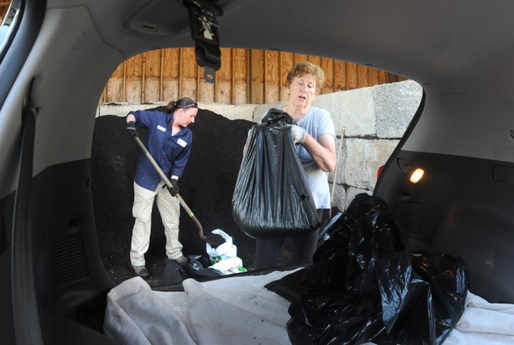 Sarah Morton, left, environmental technician with the New Hanover County Department of Environmental Management, assists county resident Debbie Riescher in loading fresh compost into her vehicle. The compost is available free to county residents with an appointment.  Photo by Mark Courtney