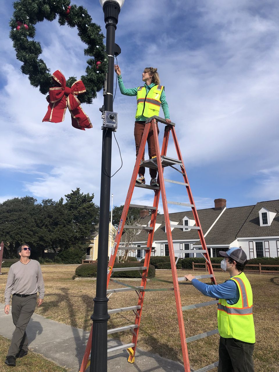 Researchers, from left, Tony Whipple, Dr. Katherine Anarde and Dr. Adam Gold set up pole-mounted sensing equipment in Beaufort in December 2021. Photo: Kerry Irish/UNC