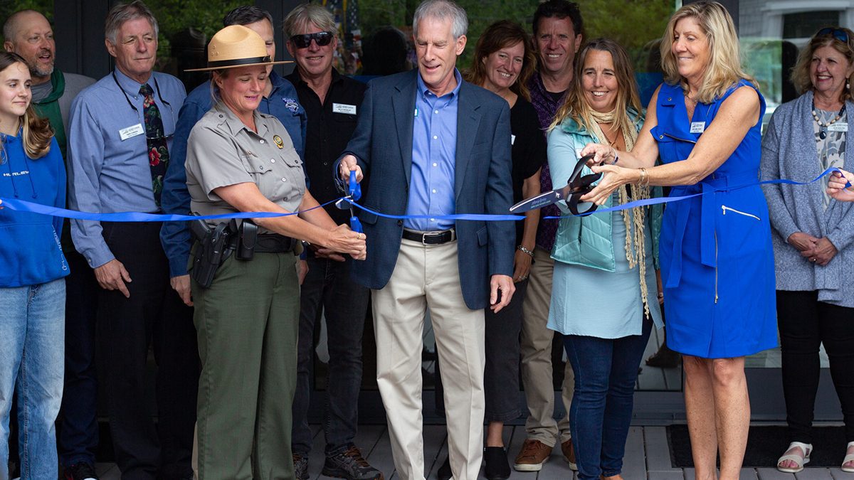 From left, Jockey’s Ridge State Park Superintendent Joy Greenwood, Department of Natural and Cultural Resources Secretary D. Reid Wilson, Friends of Jockey’s Ridge board member Lauren Nelson, and Ann-Cabell Baum, daughter of Carolista Baum and a Friends of Jockey’s Ridge board member, share two pairs of giant scissors to cut the ribbon during a ceremony at the newly renovated Jockey’s Ridge State Park visitor center as other Friends of Jockey’s Ridge board members watch from behind. Photo: Corinne Saunders
