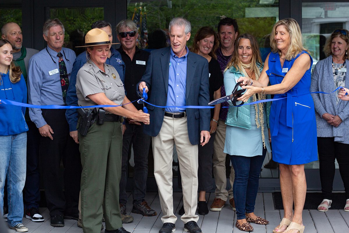 From left, Jockey’s Ridge State Park Superintendent Joy Greenwood, Department of Natural and Cultural Resources Secretary D. Reid Wilson, Friends of Jockey’s Ridge board member Lauren Nelson, and Ann-Cabell Baum, daughter of Carolista Baum and a Friends of Jockey’s Ridge board member, share two pairs of giant scissors to cut the ribbon during a ceremony at the newly renovated Jockey’s Ridge State Park visitor center as other Friends of Jockey’s Ridge board members watch from behind. Photo: Corinne Saunders