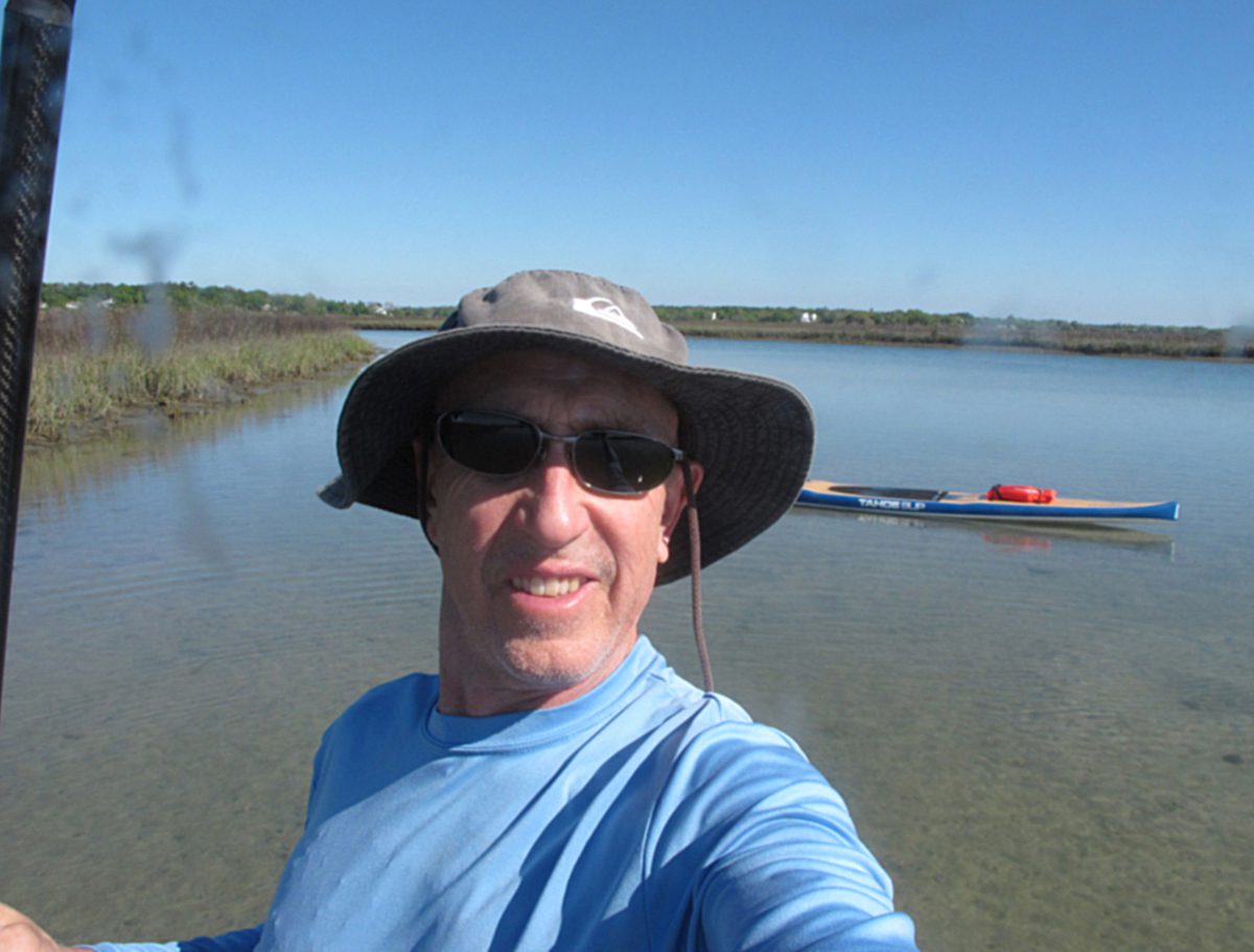Mark Courtney captures a selfie with his SUP in the background behind Figure Eight Island.