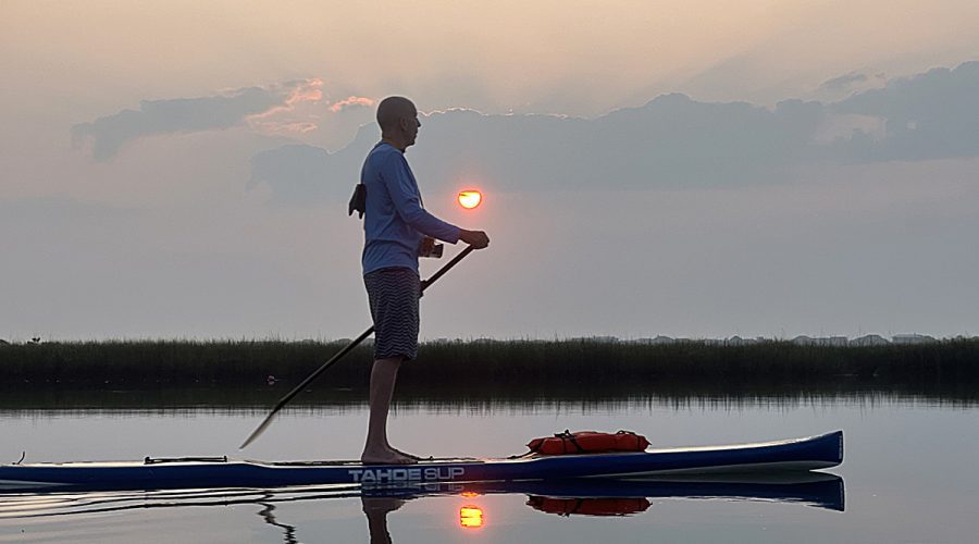 Mark Courtney paddles his SUP under perfect conditions at sunrise on June 19. The glassy stretch of water is on a salt marsh behind the barrier island, Figure Eight Island, in northern New Hanover County just outside of Wilmington. A camera enclosed in an underwater housing hangs around his neck. Photo: Cara Bloom