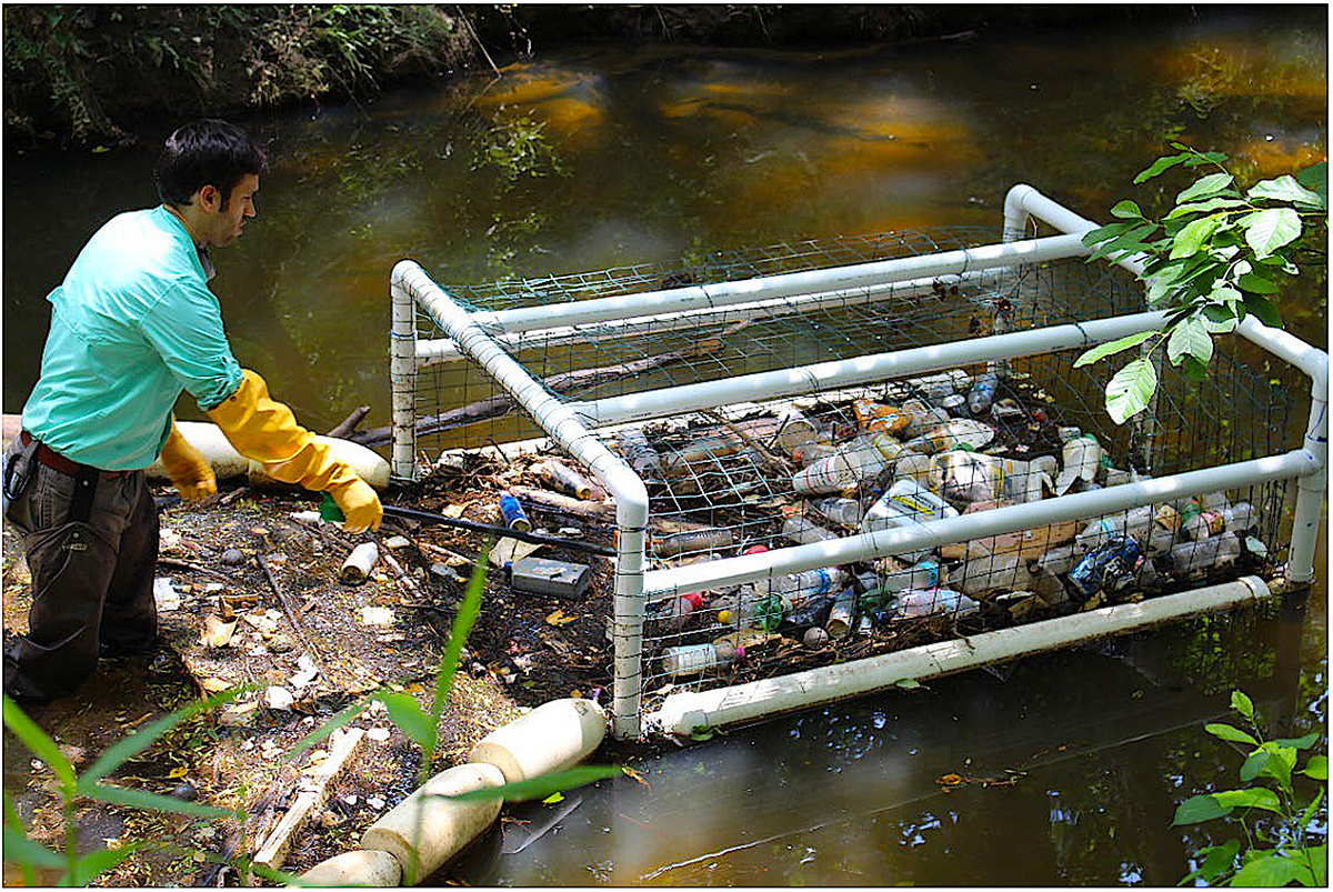 An unidentified man uses a litter getter prototype to remove litter from Marsh Creek after a storm. Photo: North Carolina Sea Grant