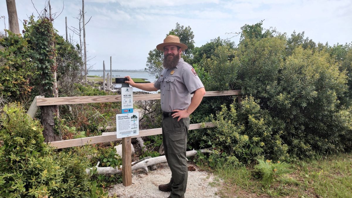 Cape Lookout National Seashore Chief of Interpretation and Education Nate Toering demonstrates how to use Chronolog, an online tool that houses crowd-sourced time-lapses of the environment, to document the ghost forest in the background. Photo: Jennifer Allen