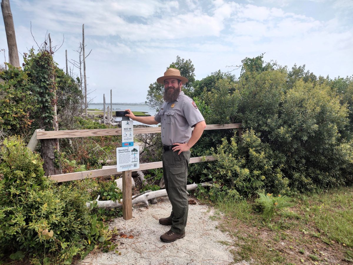 Cape Lookout National Seashore Chief of Interpretation and Education Nate Toering demonstrates how to use Chronolog, an online tool that houses crowd-sourced time-lapses of the environment, to document the ghost forest in the background. Photo: Jennifer Allen