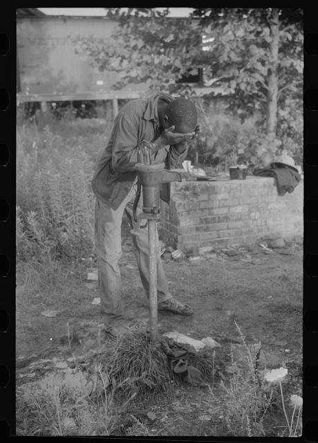 Migrant worker and water pump at a potato grading station in Camden, N.C., 1940. Photo by Jack Delano. Courtesy, Library of Congress
