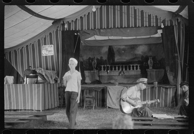 Traveling carnival, Old Trap, N.C., July 1940. According to Jack Delano, the carnival followed the path of farm workers up and down the East Coast. A typical performance included vaudeville-style acts, music, and a movie. Photo by Jack Delano. Courtesy, Library of Congress

