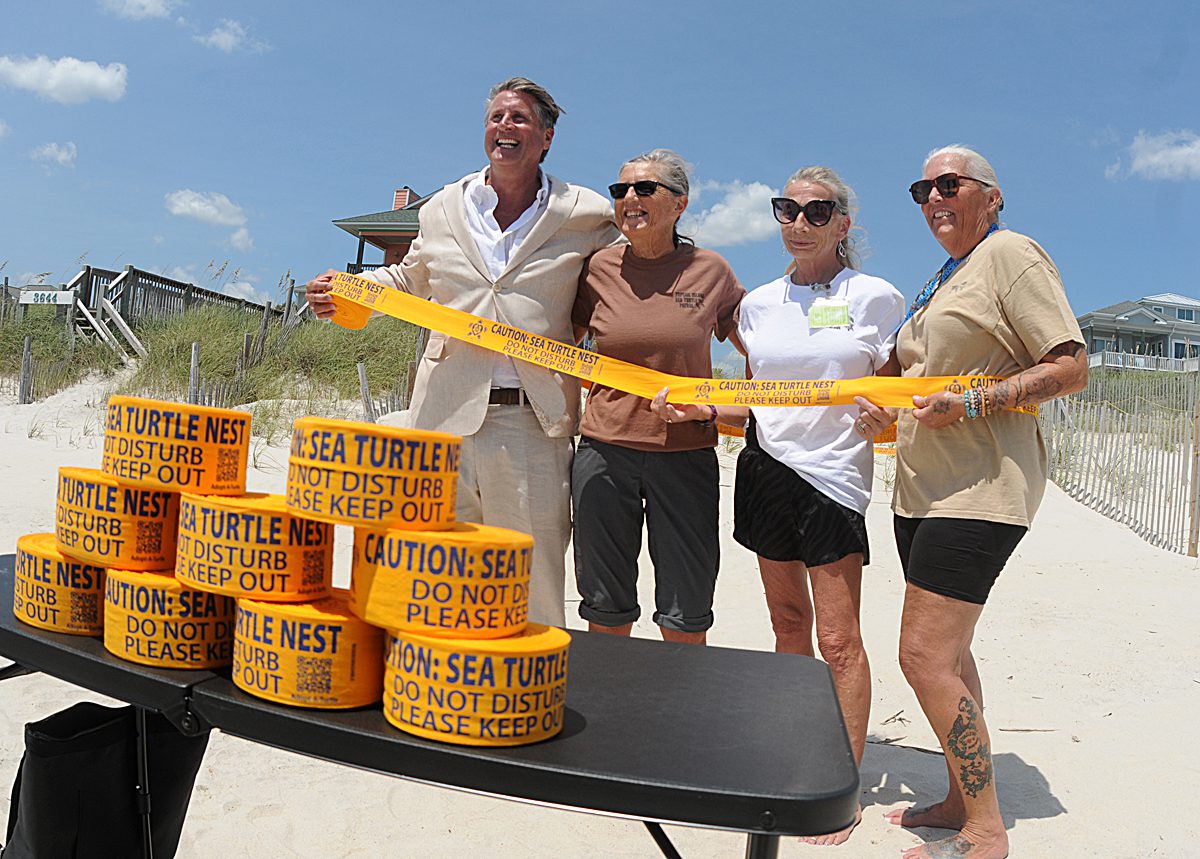 From left, Keith Dorman of Love thy turtle, Terry Meyer,  Kristy Cotter and Diana Zamora with the Karen Beasley Sea Turtle Rescue and Rehabilitation Center have fun by wrapping sea turtle nest marking tape around themselves Wednesday during a press conference promoting sea turtle awareness on North Topsail Beach. The group was announcing the use of the new ecofriendly turtle nest marking tape from Love thy turtle. Photo: Mark Courtney