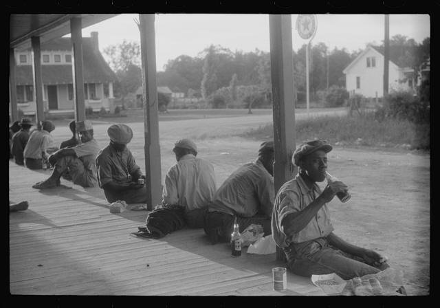 Farm workers eating supper on the front porch of the company store in Belcross, N.C., 1940. Photo by Jack Delano. Courtesy, Library of Congress

