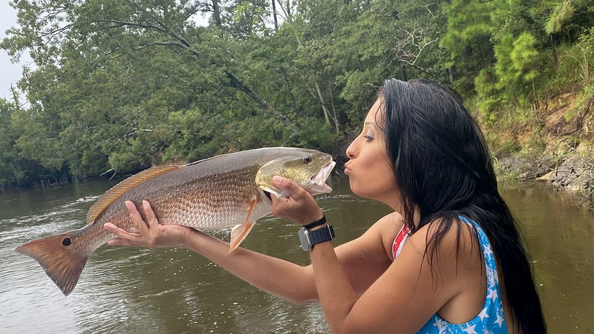 Tonya Sanders puckers up for a red drum she caught and posted at Female Fishing Fanatics, the Facebook group she started as a safe place for female anglers. Photo: Contributed