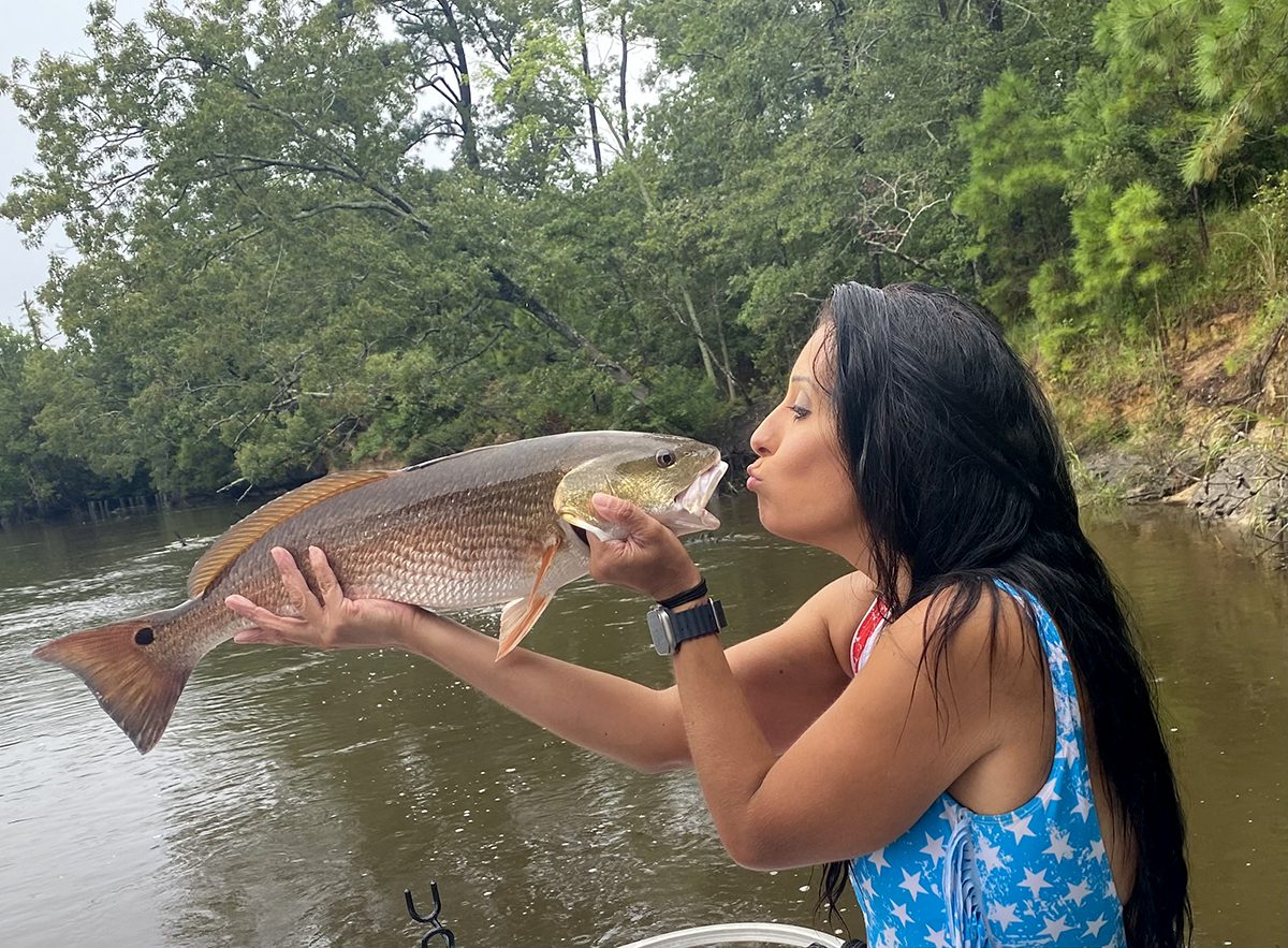 Tonya Sanders puckers up for a red drum she caught Aug. 30 and posted at Female Fishing Fanatics, the Facebook group she started as a safe place for female anglers. Photo: Contributed