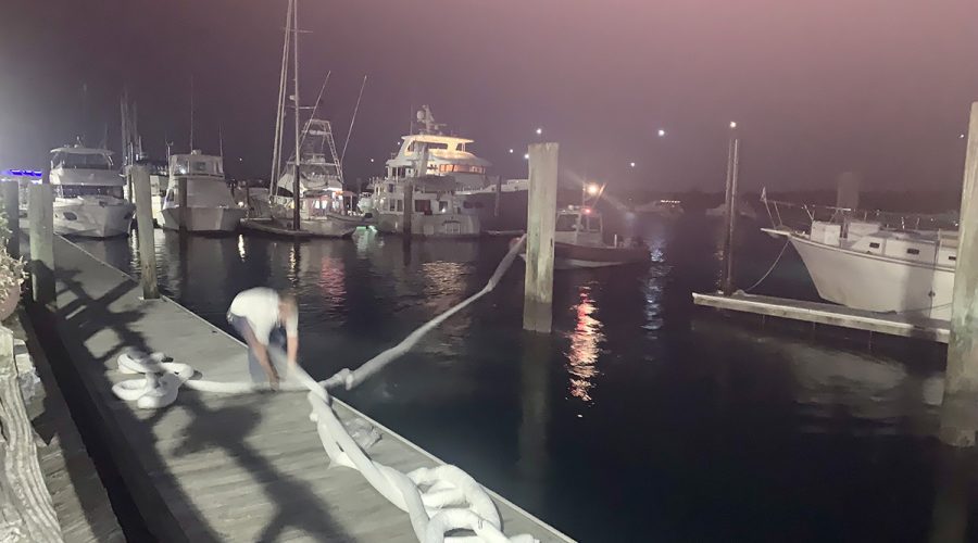 A team from Atlantic Coast Marine Services places booms in the water around the diesel fuel spill at the Beaufort Docks Saturday night. Photo: Mark Hibbs