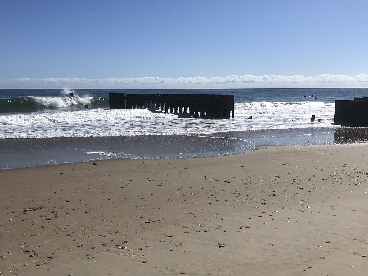 A wave breaks over the remains of what surfers call the First Jetty at the former site of the Navy listening station at Cape Hatteras. Photo: Carol Busbey
