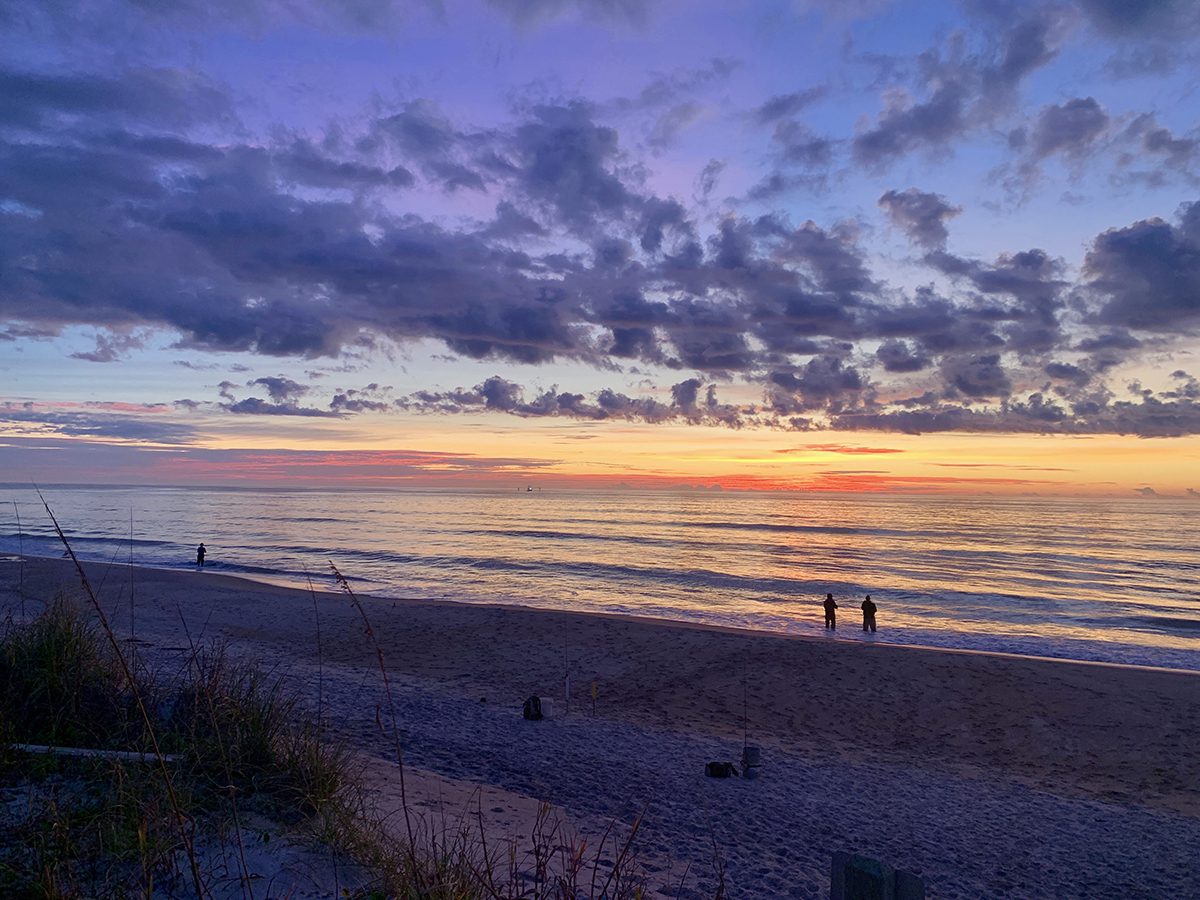 Fishing rod on a beach at sunset, landscape with a city in the