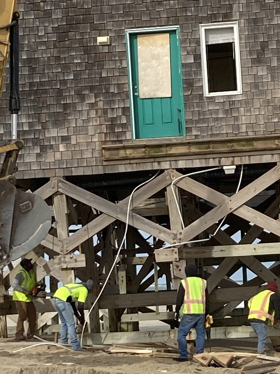 Workers use saws to cut through parts of one house's lower structure Wednesday on the Cape Hatteras National Seashore. Photo: Catherine Kozak
