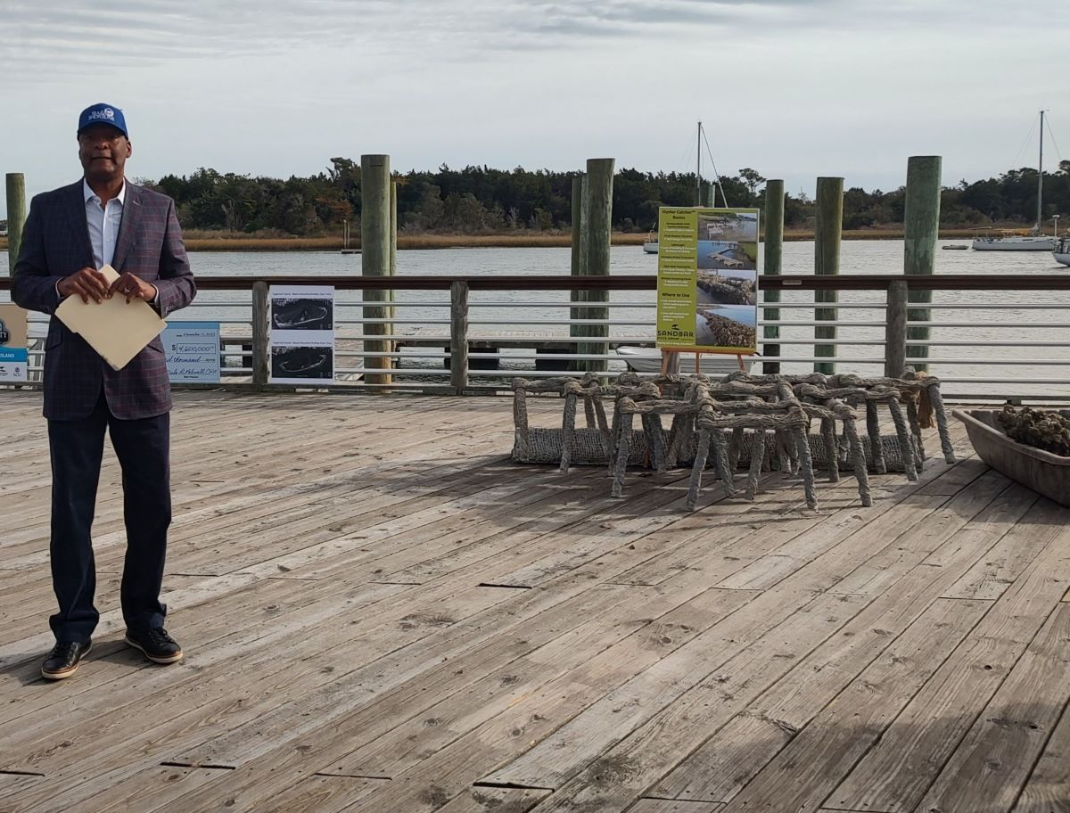 Brian Henry, director of Florida-based Sea & Shoreline's North Carolina and South Carolina offices, speaks Wednesday to a small group about work to preserve Sugarloaf Island, in the background. Photo: Jennifer Allen