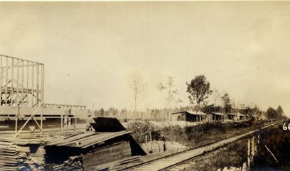 This is a remote labor camp called Wonderland, on the border of Washington County and Beaufort County, N.C., November 1917. The railroad tracks are those of the Norfolk & Southern. On the left, we can see a commissary and post office being built. On the right, we can see barracks for some of the hundreds of black workers that were employed in logging, clearing, and burning and re-burning what was left of the East Dismal Swamp. After logging the swamp forest, the Roper Lumber Co. had sold 40,000 acres of its holdings in the East Dismal to Mark W. Potter, a wealthy New York attorney who was president of the Ohio, Clinchfield & Carolina Railway Co. (a subsidiary of the Norfolk and Southern). Going into business with local lumbermen and land developers John A. and Samuel Wilkinson (more on them later), Potter aimed to reclaim the logged swamplands, subdivide the land, and sell plots to farmers recruited mainly in the Midwestern states. However, according to federal records, Wonderland only had a post office from 1917 to 1925. Once the ground was made ready for farming, the little settlement disappeared and was soon forgotten. Other land developers attempted similar projects on the Roper Lumber Co.’s former holdings. According to a WPA interview with Samuel Wilkinson in 1938, most, including the Wilkinson brothers, ended up making little if any profit, in large part due to the ongoing costs of draining the land. By the time that they added up their losses however, only a scattered few thousand acres of the East Dismal had not been logged, drained, burned repeatedly, and turned into farmland. From Views of Potter Farms Development: Showing Various Stages in the Evolution of Potter Farms (1917),  North Carolina Collection, Wilson Library, UNC-Chapel Hill

