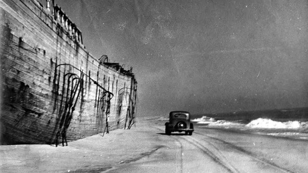 Driving down Outer Banks beach by shipwreck. Photo: D. Victor Meekins Papers, Outer Banks History Center