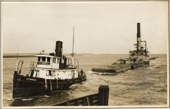 A final look at the Army Corps of Engineers’ crews at work. In this case, we see the Corps’ tug Richard Caswell towing the pipe-line dredge Currituck at Beaufort, N.C., February 1931. The tug’s crew has its hands full: the two vessels have come south down the Intracoastal Waterway (IWW) and are approaching the Norfolk & Southern Railroad’s bridge in a stiff northeast wind and a roiling tide. They made it, but only after tying up the Currituck’s pontoons on the bridge escarpment and then having the tug go back and retrieve them after the Currituck made it to the other side. The Richard Caswell was one of several tugs that towed dredge boats and barges for the Army Corps of Engineers’ Norfolk District. Like all tugs, she was a stout, seaworthy craft, and her 9-man crew had to be tough sailors who knew their jobs. Built in Southport, N.C., in 1913, the Caswell was an 84.9 ft.-long tug with a displacement of 200 tons. On the day shown here, she was leading the Currituck to a rendezvous with a larger, oceangoing tug on the other side of the Beaufort Bar. That tug would take her south of Wilmington to begin work on a new section of the IWW. Source: Office of History, HQ, U.S. Army Corps of Engineers
