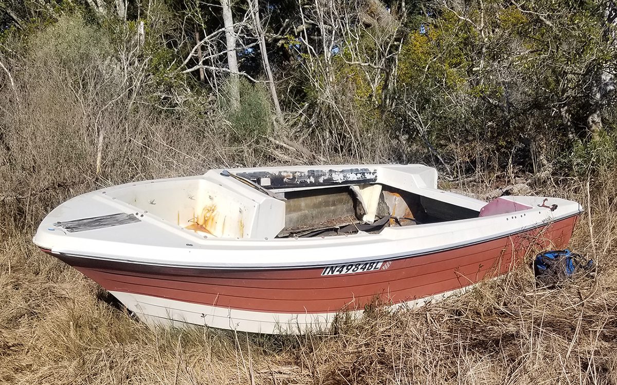 An abandoned pleasure craft rests in the marsh near Topsail Island before its removal in 2023. Photo: North Carolina Coastal Federation