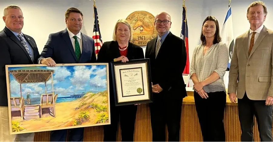 Renee Cahoon, center, poses with her framed Order of the Long Leaf Pine award presented by, from left, Commissioner Kevin Brinkley, Mayor Pro Tem Mike Siers, Mayor Ben Cahoon, and commissioners Megan Lambert and Bob Sanders. Photo: Nags Head