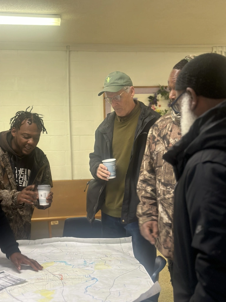 BJ Herring, Nick Smith, Vinnie Joyner, and I looking over the 1913 survey map of Piney Grove with our morning cups of coffee. Photo by David Cecelski
