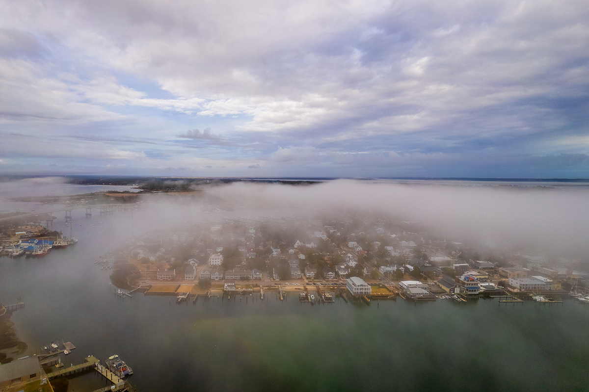 A late winter fog blankets Beaufort's historic downtown in this recent aerial view. The Gallants Channel Bridge is visible at the upper left, Pivers Island and the National Oceanic and Atmospheric Administration Beaufort Laboratory docks, lower left. Photo: Dylan Ray